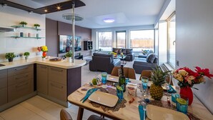 Een moderne keuken met een eethoek, grote ramen en uitzicht op de achtertuin.