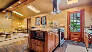 A spacious kitchen with a central island, wooden cabinets, and a large window.