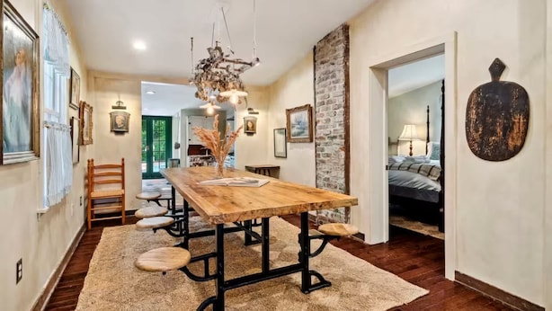 A dining area with a wooden table, chairs, and a rustic chandelier.