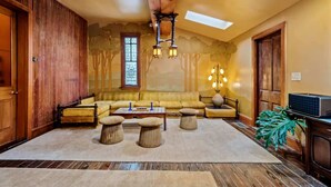 A cozy living room with a wooden ceiling, a large window, and a sofa set.
