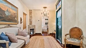 A hallway with a sofa, a chair, a fireplace, and a painting on the wall.