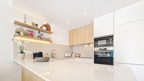 A modern kitchen with a large island, wooden cabinets, and built-in appliances. - Villa with private pool, roof terrace and BBQ (Los Alcazares)