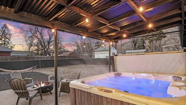 A hot tub under a covered patio with a fire pit and outdoor seating. - The Gray Pine | Hot Tub, Fire Pit, Office + A/C (Flagstaff)