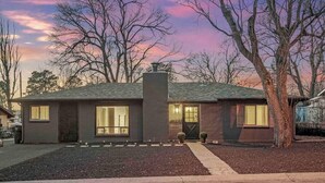 A single-story house with a dark roof, large windows, and a chimney. - The Gray Pine | Hot Tub, Fire Pit, Office + A/C (Flagstaff)
