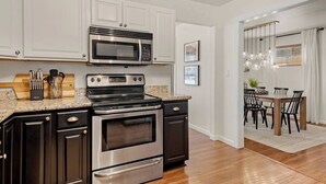 A modern kitchen with stainless steel appliances, dark cabinetry, and a wooden countertop. - The Gray Pine | Hot Tub, Fire Pit, Office + A/C (Flagstaff)