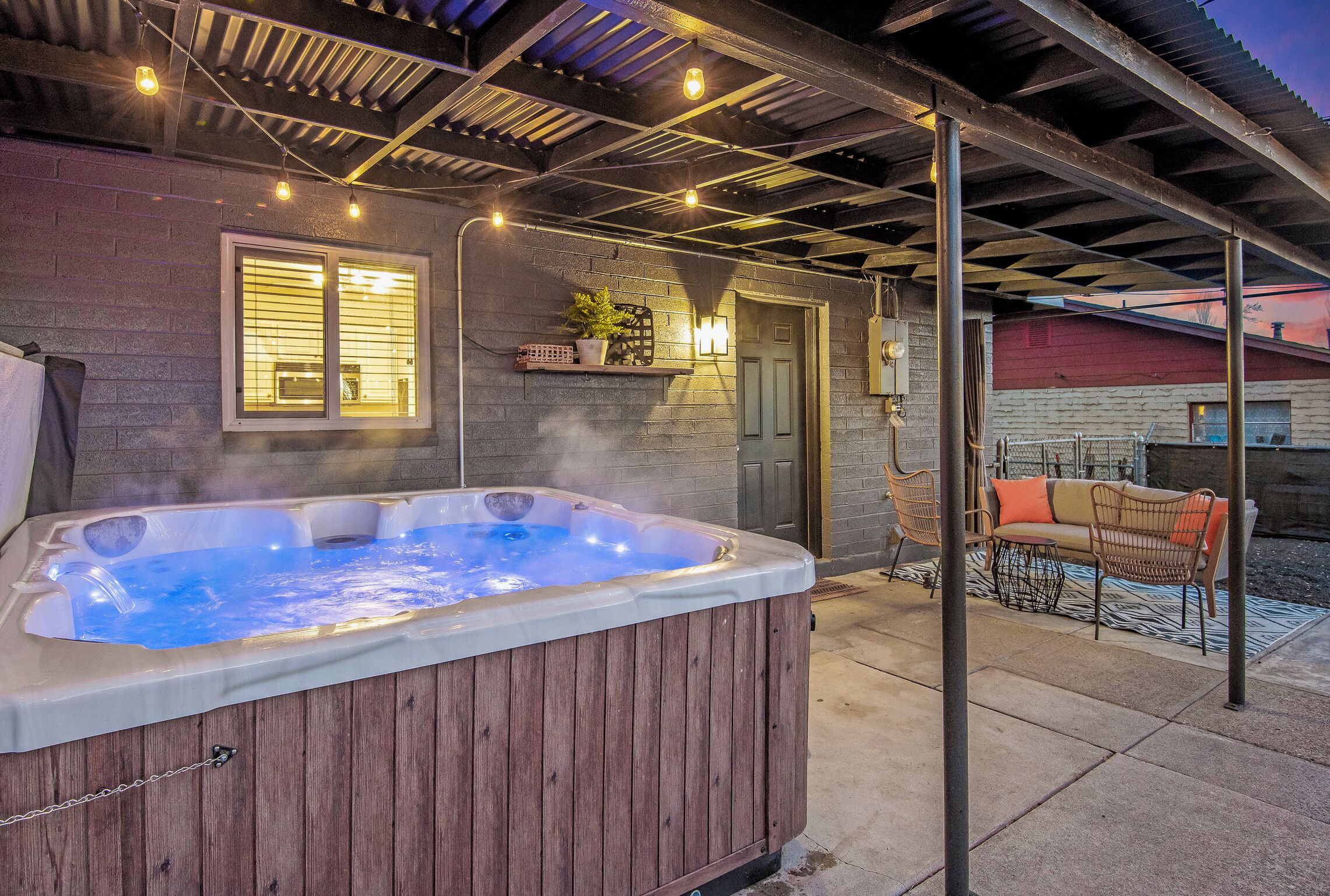 Un bain à remous situé dans un espace extérieur abrité, avec une terrasse et des sièges.