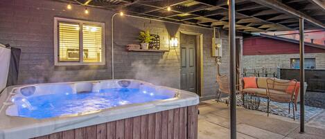 A hot tub in a covered outdoor area with a patio and seating.