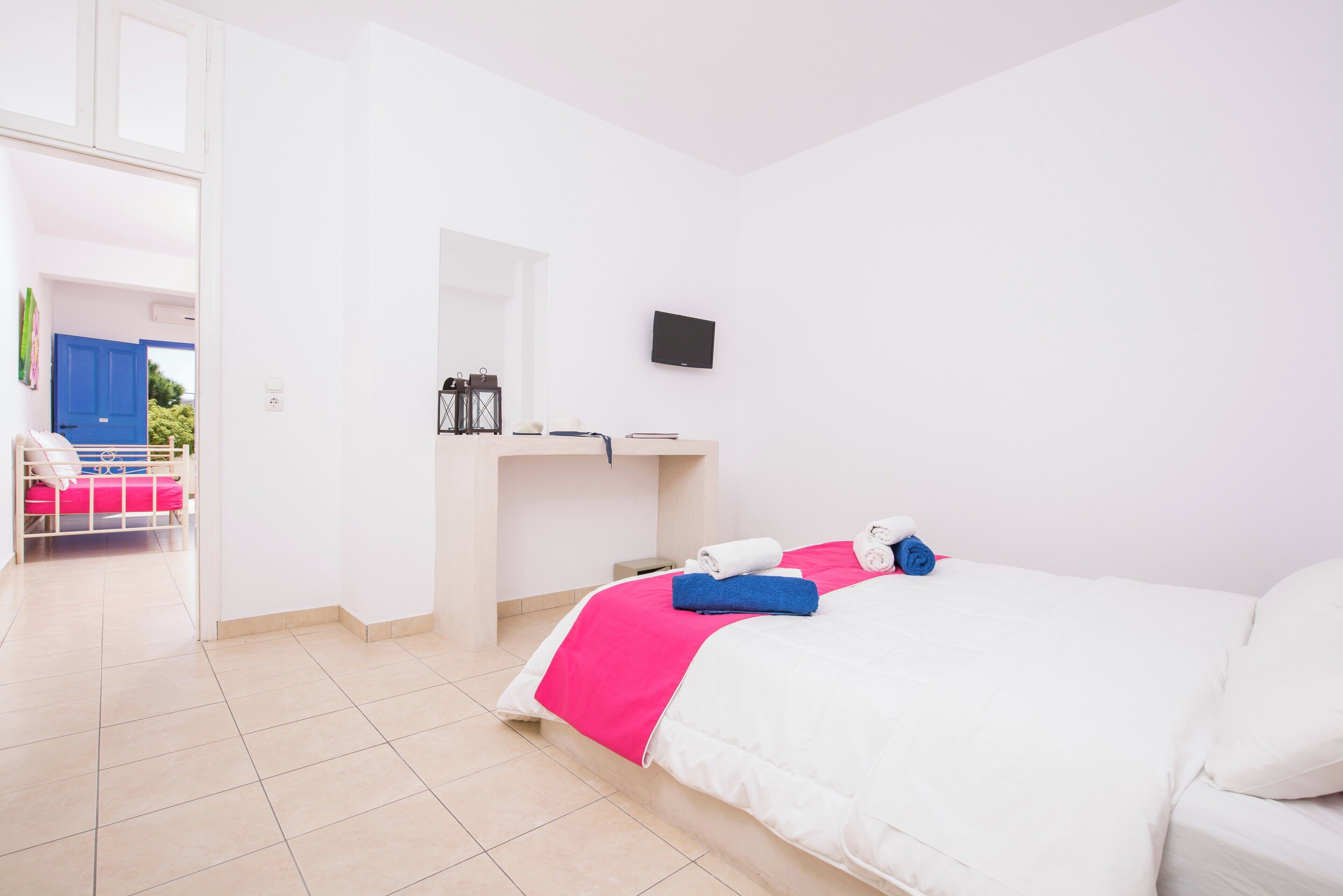 A hotel room with a bed, a desk, a television, and a view of the outside.