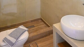 A bathroom with a toilet, a sink, and wooden flooring. - 1-bed Apt at Hotel, Near Perivolos Black Beach (Santorini)