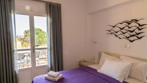 A hotel room with a bed, a phone, a wall art piece, and a view of the outdoors. - 1-bed Apt at Hotel, Near Perivolos Black Beach (Santorini)