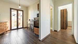 A spacious kitchen with wooden flooring, a dining area with stools, and a sliding glass door leading to an outdoor area. - Apartment 'Sa Domixedda' in Quartu Sant'Elena – Central, Renovated, Near Poetto Beach (Quartu Sant'Elena)