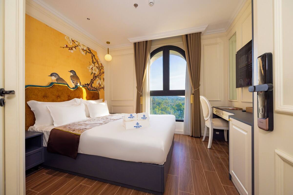 A hotel room with a large bed, a desk, and a view of the outdoors.
