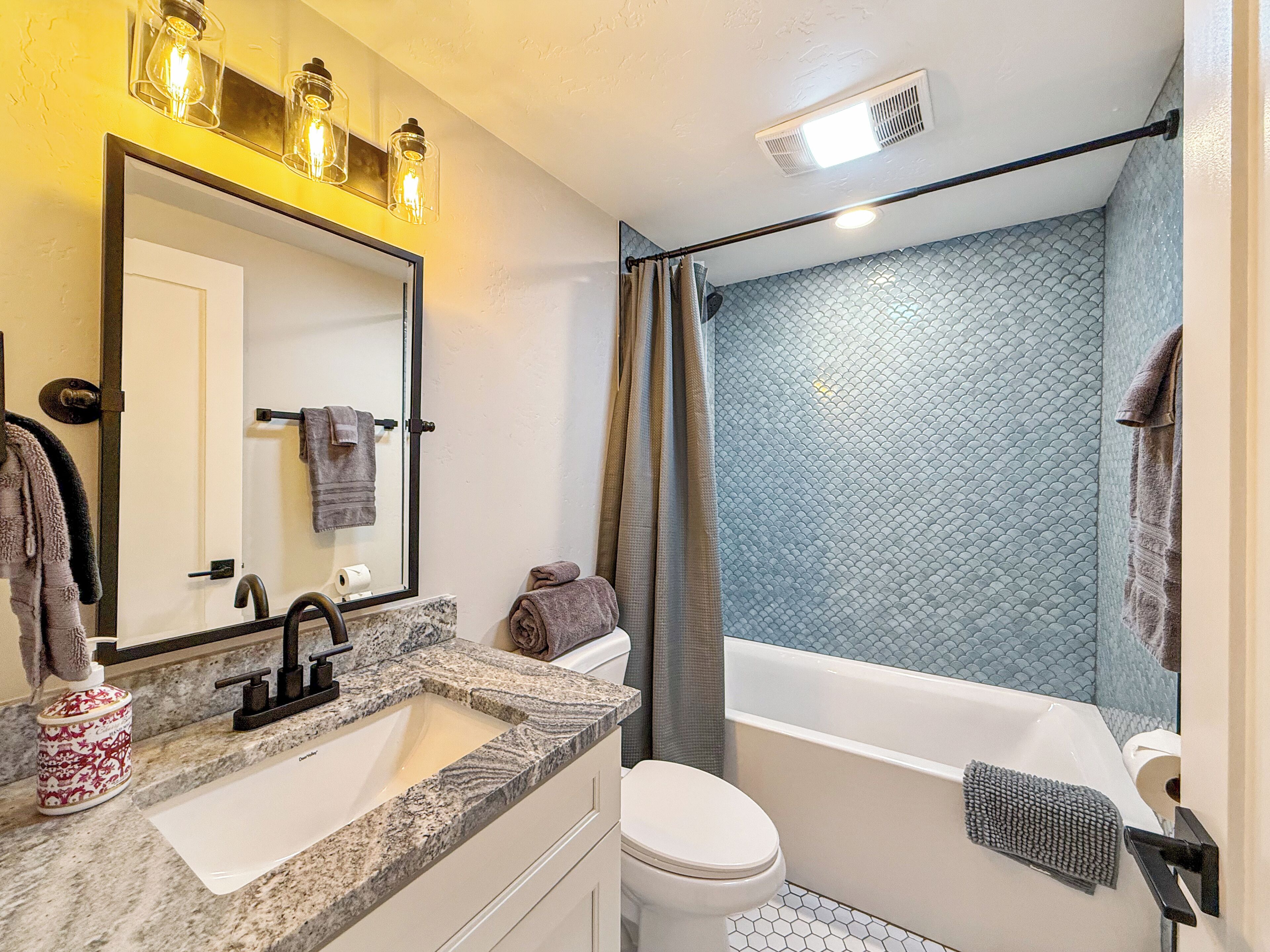 Un baño con lavamanos de mármol, inodoro y bañera.
