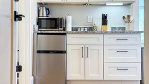 A modern kitchen with white cabinetry, stainless steel appliances, and a marble countertop. - The Globe Mallow Suite at The Hesch - Premier Location - Railyard Arts District (Santa Fe)