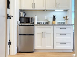 Una cocina moderna con armarios blancos, electrodomésticos de acero inoxidable y encimera de mármol.