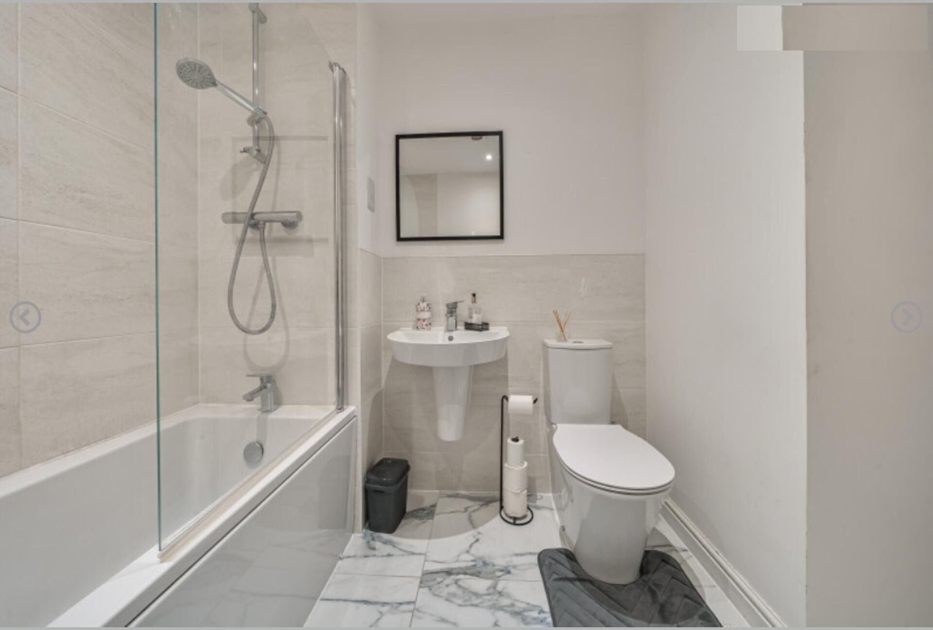 A modern bathroom with a glass-enclosed shower, a pedestal sink, and a toilet.