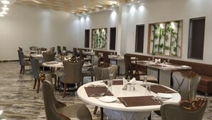 A hotel dining area with round tables, chairs, and a modern ceiling design. - The Sky Imperial Chotila (Chotila)