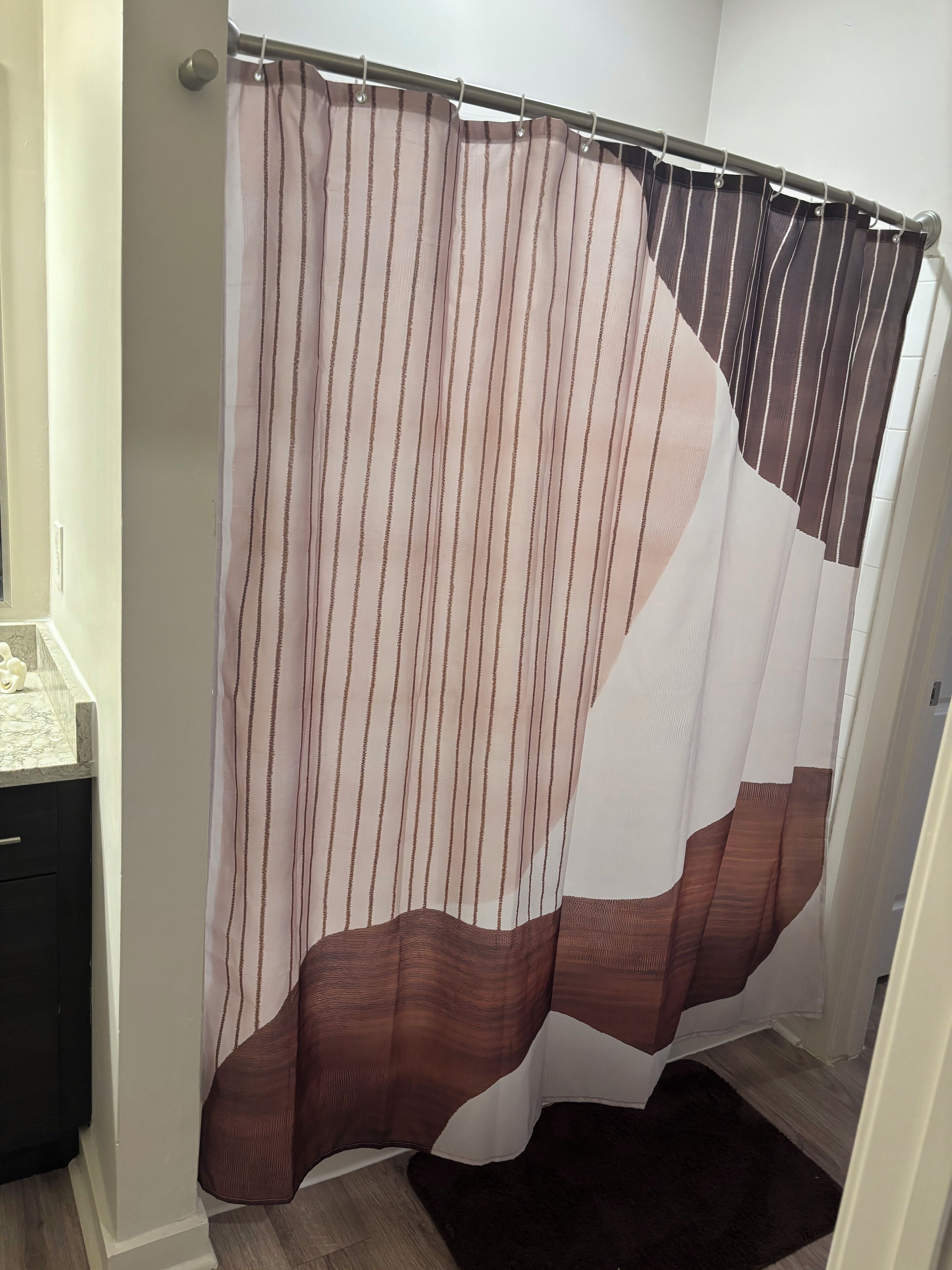 A bathroom with a shower curtain featuring a striped pattern and a brown design.