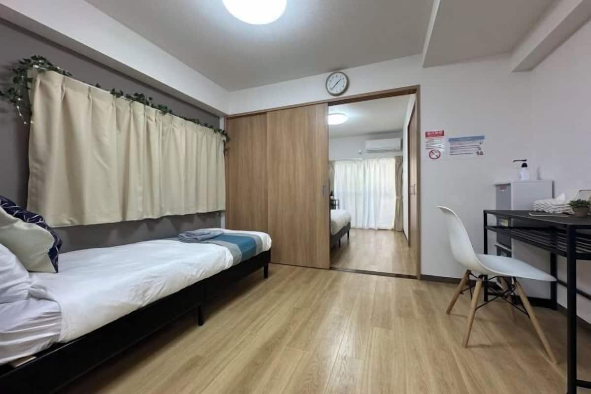 Un dormitorio con una cama, un escritorio y una silla. Hay una puerta que da a otra habitación.