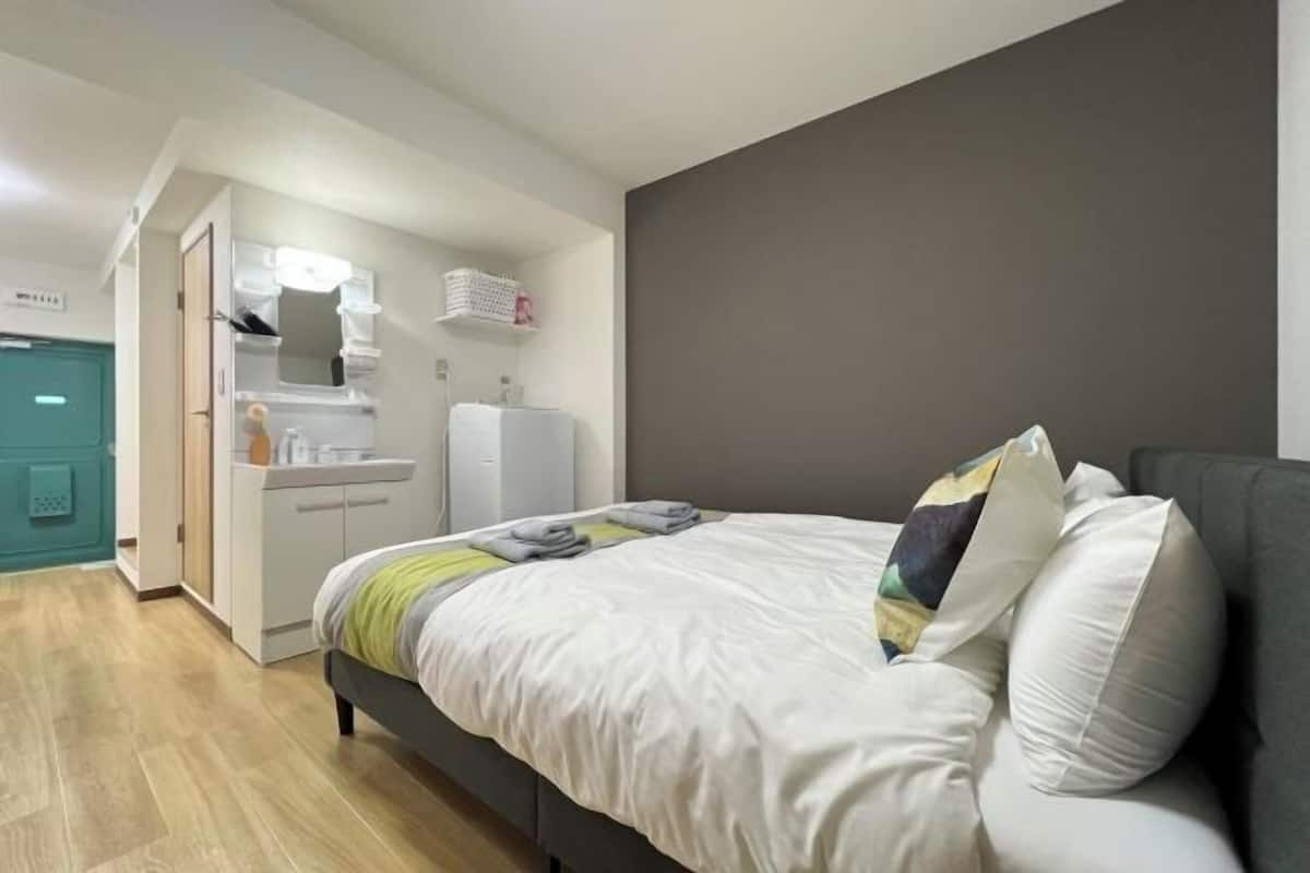 Un dormitorio con cama, armario, kitchenette pequeño y baño.