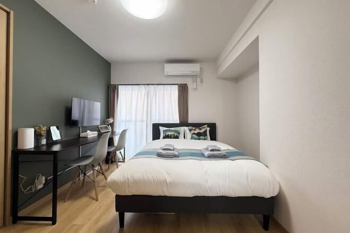 Un dormitorio con cama, escritorio, silla y televisor.