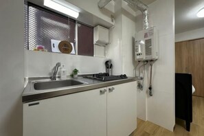 Una cocina con pileta, estufa y sistema de ventilación.