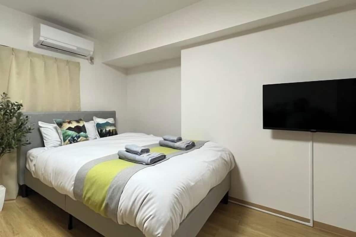 Una habitación de hotel moderna con una cama, un televisor de pantalla plana y una planta en maceta.