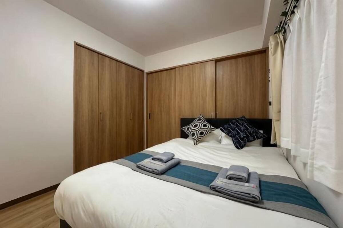 Un dormitorio con cama, armario de madera y ventana con cortinas.