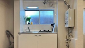 Una cocina compacta con ventana, estufa integrada y un aspirador.