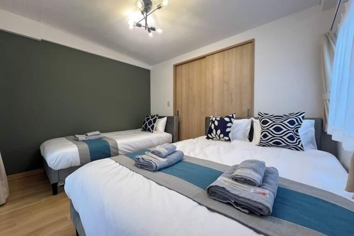 Una habitación de hotel con dos camas, un armario de madera y una lámpara en el techo.