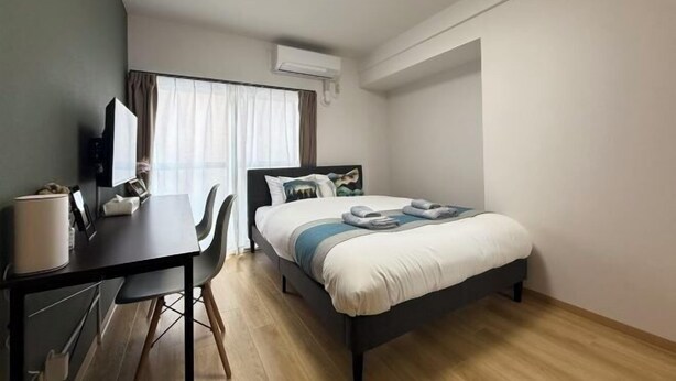 Un dormitorio moderno con cama, escritorio y silla.