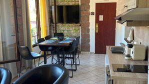 A modern kitchen with a dining area, featuring a wooden countertop, a built-in oven, and a TV mounted on a brick wall. - Very pleasant apartment with sea and mountain views, boat trip (Ota)