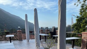 An outdoor patio with tables and chairs, covered umbrellas, and a potted plant. - Very pleasant apartment with sea and mountain views, boat trip (Ota)