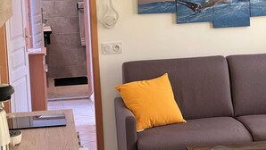 A modern living room with a grey sofa, a wooden coffee table, and a kitchen area with a sink and countertop. - Very pleasant apartment with sea and mountain views, boat trip (Ota)