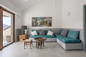 A modern living room with a sofa, a small round table, and a painting on the wall.