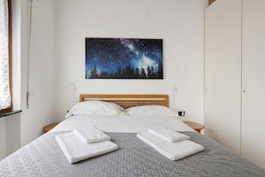 A hotel room with a bed, a night sky mural, and neatly folded towels on the bed.