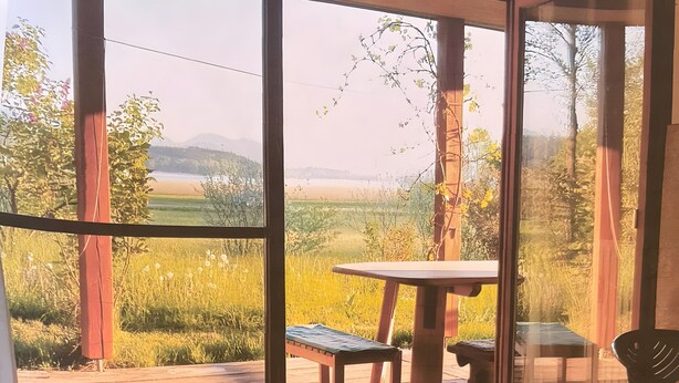 Ein Zimmer mit einem großen Fenster, einem Holztisch und einer Bank.