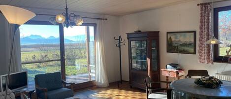 A room with a large window, a dining table, a television, and a sofa.