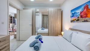 Une chambre d’hôtel avec un lit, une table de chevet, un tableau et une salle de bain visible à travers une porte ouverte.