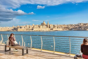 A waterfront promenade with benches overlooking a cityscape. - Charming 2bedroom flat, creek view balcony EMAG1-1 (Sliema)