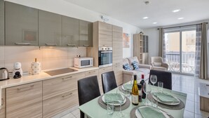 Une cuisine moderne dotée d’appareils électroménagers intégrés, un coin repas avec une table pour quatre personnes et un balcon avec vue.