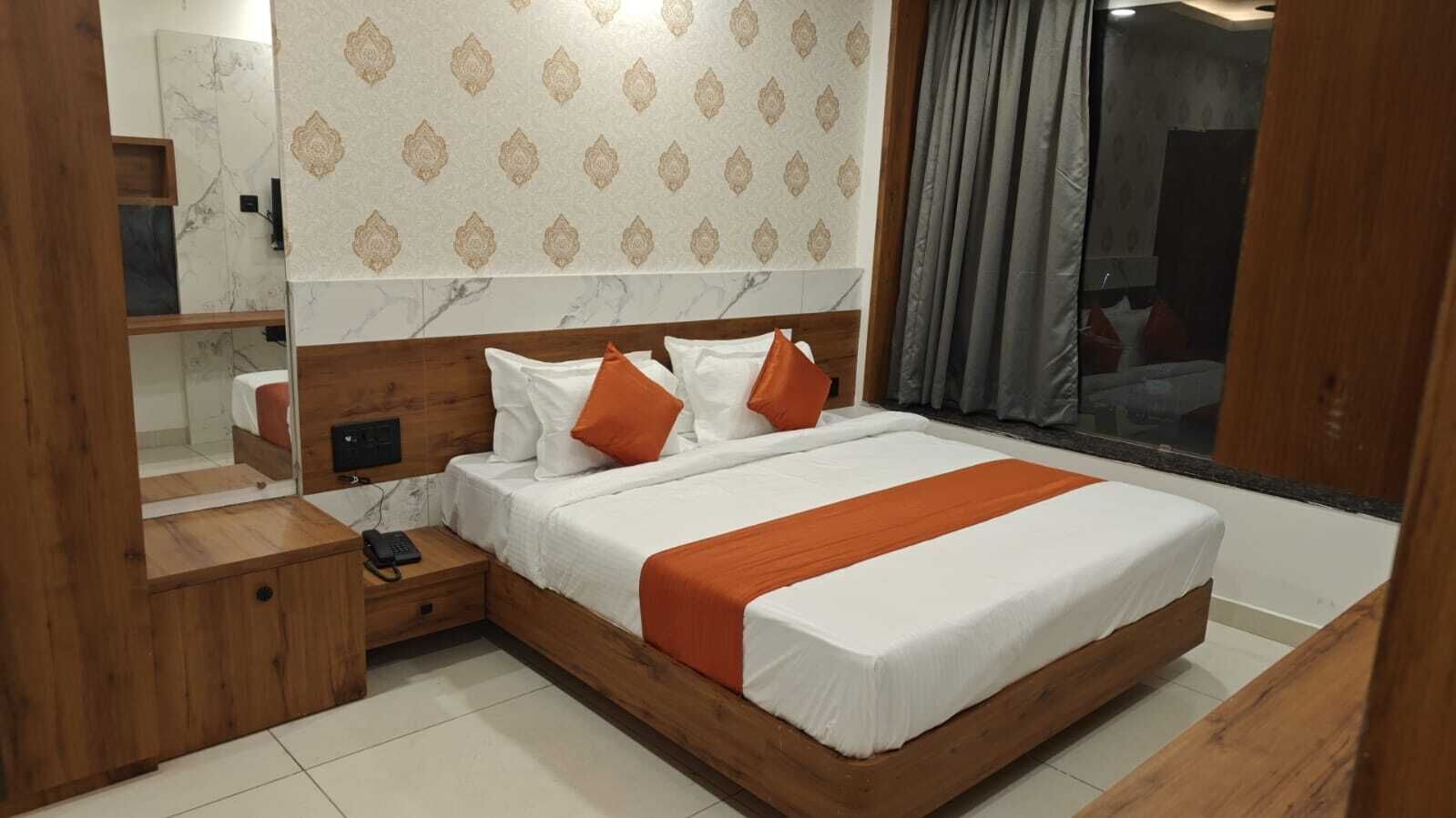 Une chambre à coucher moderne avec un cadre de lit en bois, du linge de lit blanc et des touches de couleur orange.