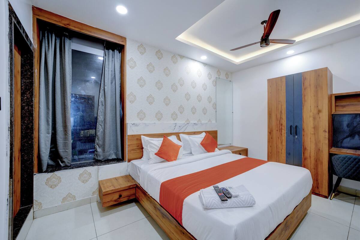 A bedroom with a large bed, wooden wardrobe, and a ceiling fan.