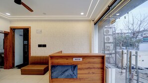 A reception area with a wooden reception desk, a bench, and a view through a glass door. - The Byke Boutique Urban Nest (Bhopal)