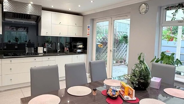 A modern kitchen with white cabinets, a black countertop, and a dining area with a dark wooden table and grey chairs. - Peaceful, Spacious Home Minutes from Centre (Chester)