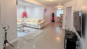 A modern living room with a sofa, a rug, a television, and a camera on a tripod. - Peaceful, Spacious Home Minutes from Centre (Chester)