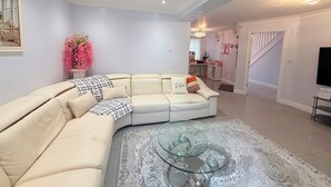 A living room with a beige sectional sofa, a glass coffee table, and a staircase leading to another level. - Peaceful, Spacious Home Minutes from Centre (Chester)