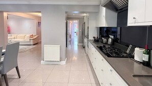 A modern kitchen with a central island, white cabinetry, and a stainless steel range hood. - Peaceful, Spacious Home Minutes from Centre (Chester)