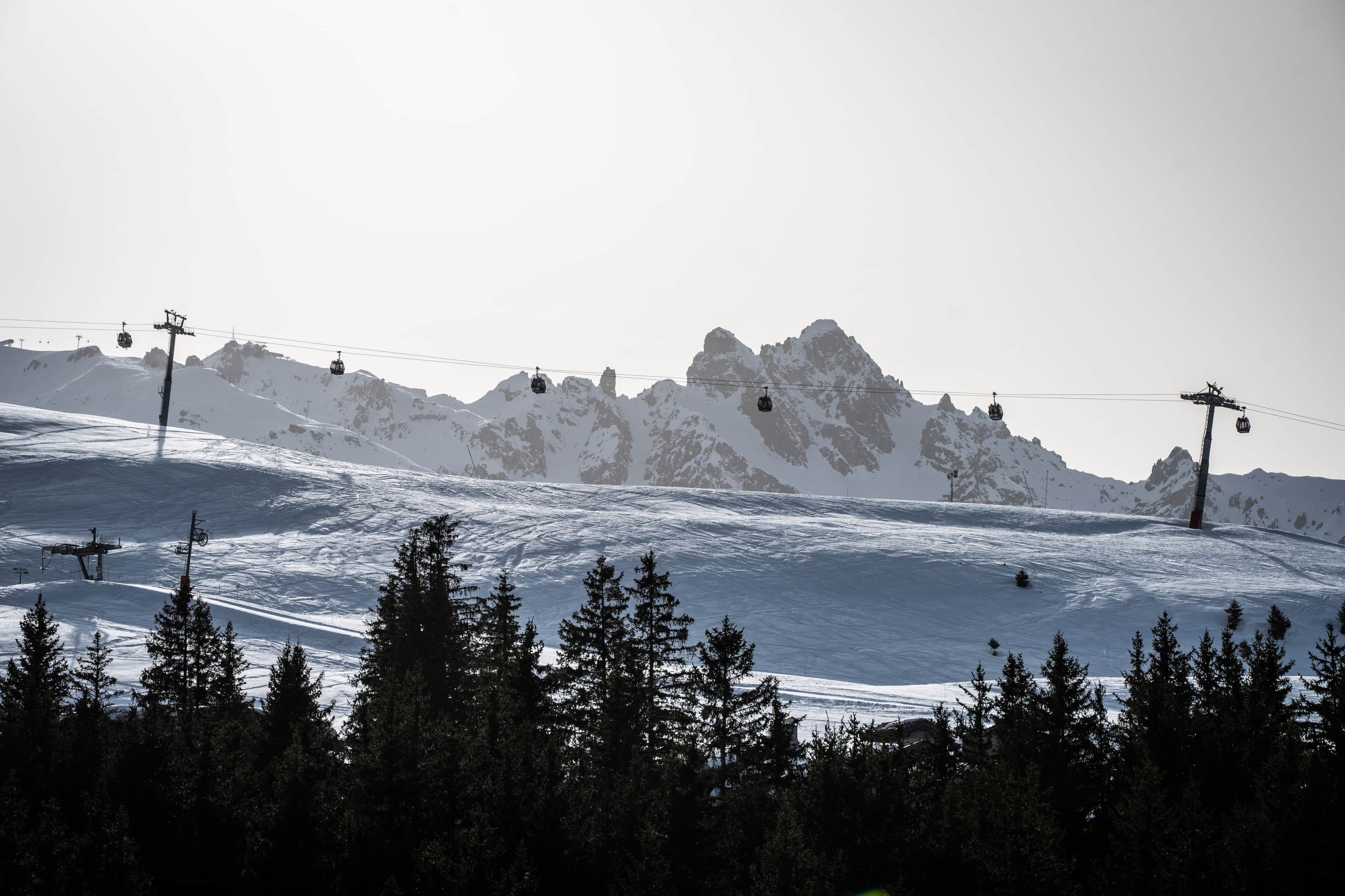 Een besneeerd berglandschap met skiliften en bomen.