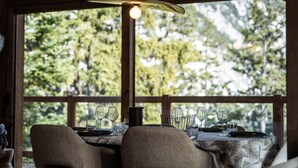 A dining table set with wine glasses and a pitcher, positioned near a window with a view of trees. - Penthouse in Courchevel Moriond, Belvédère area (Courchevel)